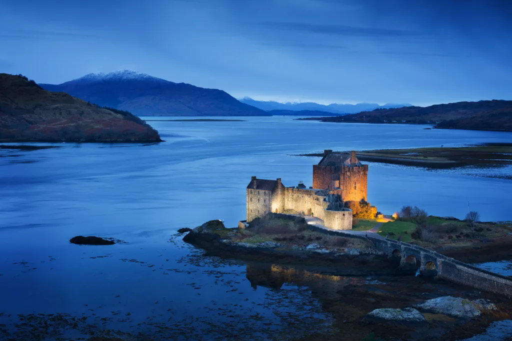 Eilean Donan Castle lit up at dusk in the Scottish Highlands, Scotland