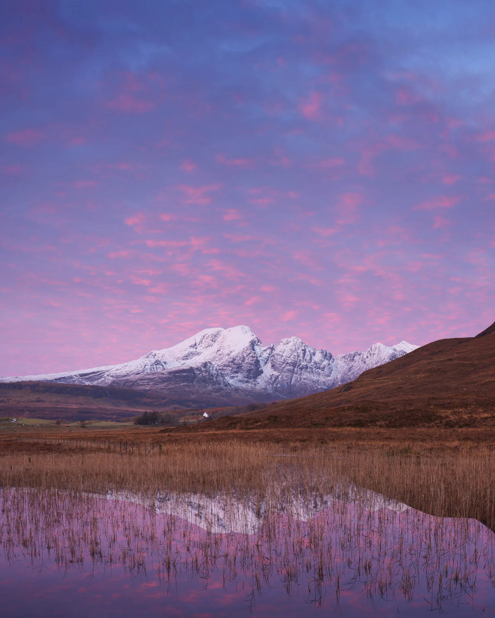 Bla Bhienn and Chlach Glas mountains with snow capped peaks reflected in 'the hairy loch' Loch Cill Chroisd at sunrise on The Isle of Skye travel photographer Scotland