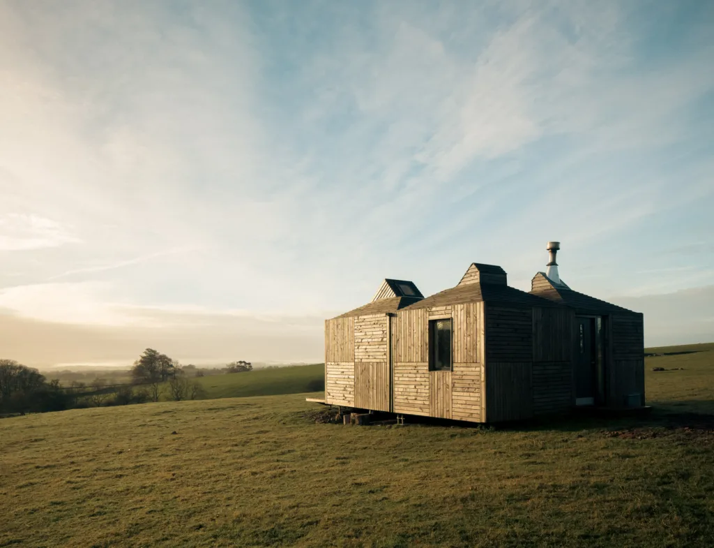 Architect designed modular eco bothy with timber cladding pitched roofs with solar panels set in open field