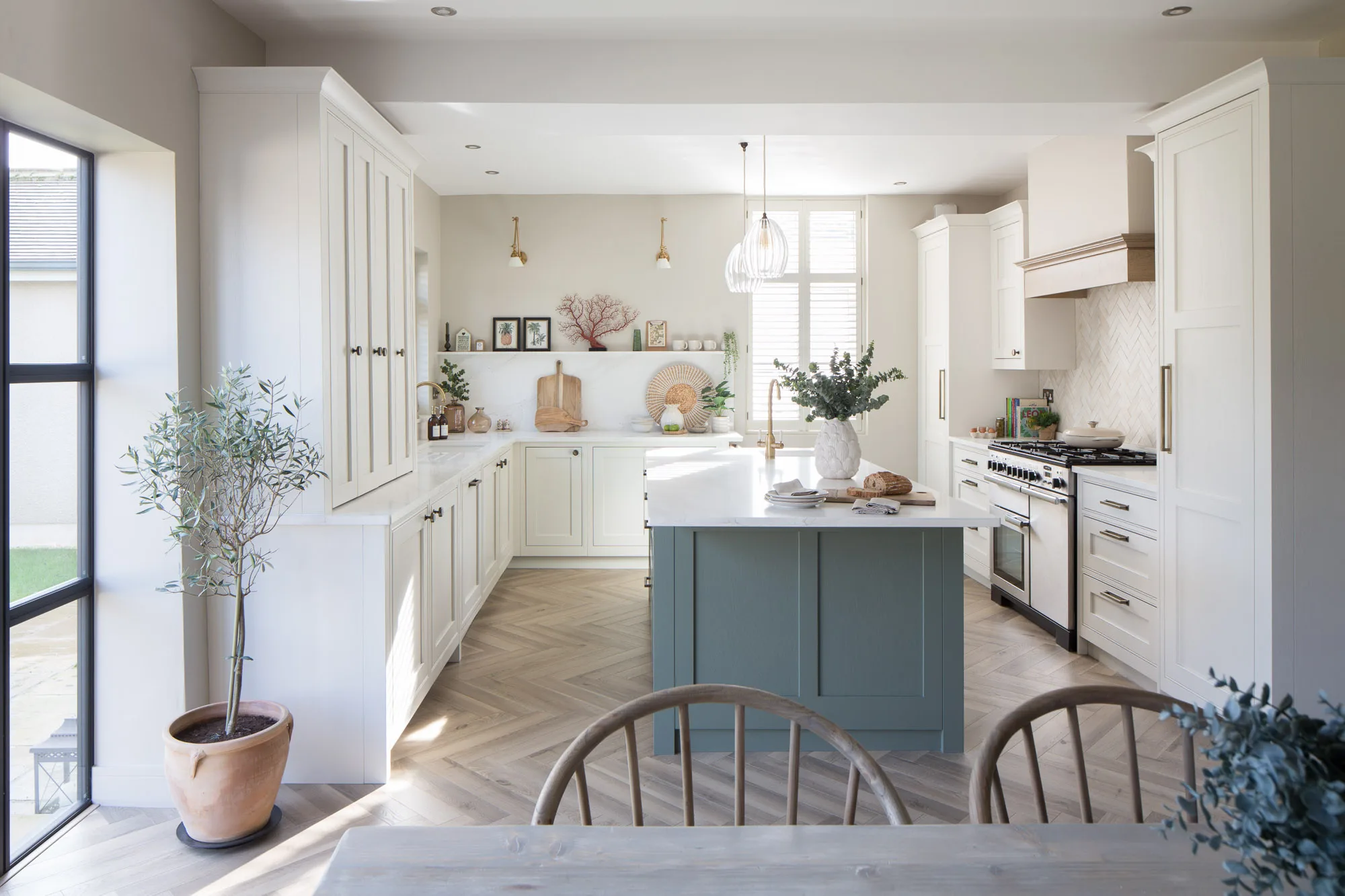 Photograph of kitchen installation for interior designer. Light painted shaker units with soft green island, black aluminium crittal doors